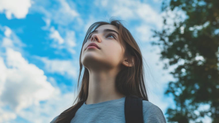 A teenager with a backpack looking up at a blue sky | TMS Therapy for Adolescents: A New Hope in Teen Depression Treatment | Mindful Health Solutions