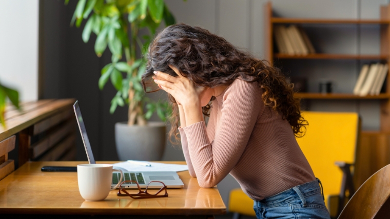 Woman at her desk with her head in her hands | How to Request a Mental Health Day Achieving Work-Life Balance with Time Off