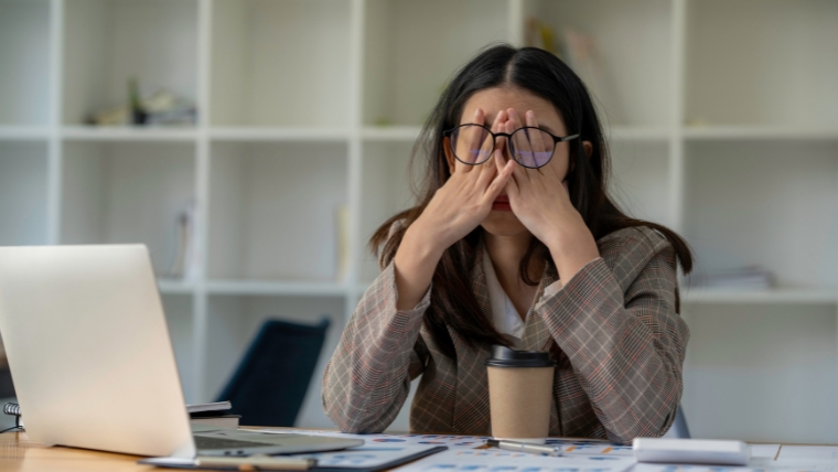 8 Unexpected Reasons Female person at desk with hands on face, looking stressed, overwhelmed, and burnt out | Why Perfectionism Is Bad for Your Mental Health | Mindful Health Solutions