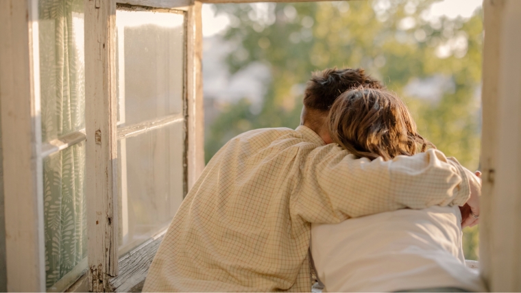 A couple leaning out a window with their arms around each other | Is Your Relationship Healthy or Codependent? How to Know for Sure | Mindful Health Solutions