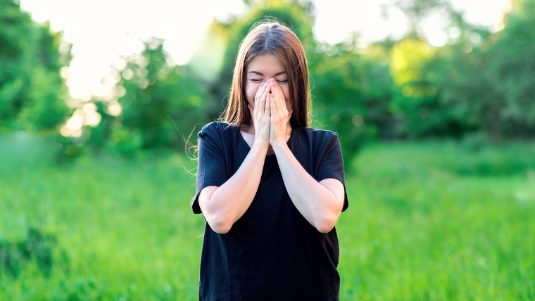 Young woman standing in field smiling with hands over her mouth | Did You Know 7 Shocking Facts About Esketamine Therapy | Mindful Health Solutions