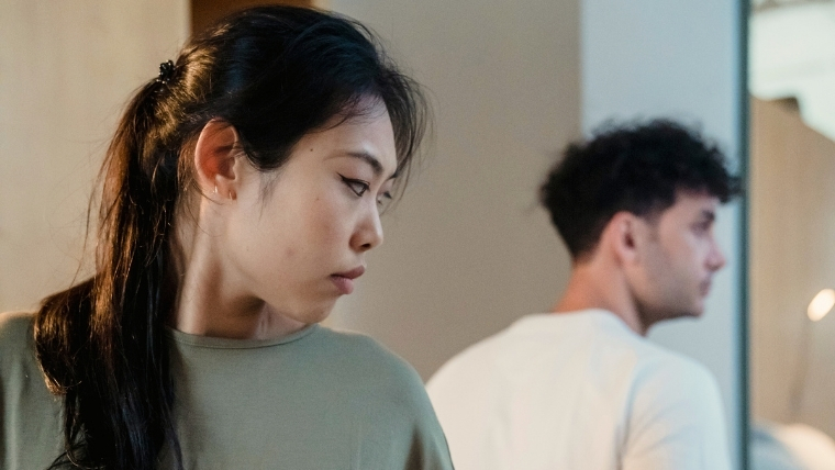 A woman looking over her shoulder at her male partner, both avoiding eye contact and looking sad and serious | How Depression Impacts Your Relationships and 16 Effective Coping Strategies | Mindful Health Solutions