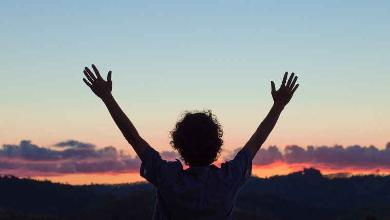 A silhouette of a person with open arms in front of a sunset | How To Transform Your Life with a Consistent Gratitude Practice | Mindful Health Solutions