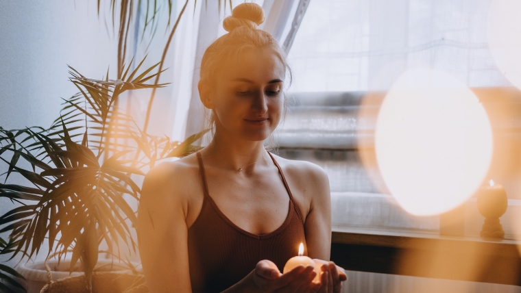 Woman smiling to herself while holding a candle | Celebrate Self-Love Expert Strategies to Embrace Valentine's Day After a Breakup | Mindful Health Solutions