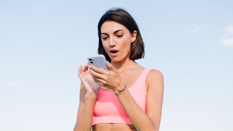 A woman looking at her phone with a shocked expression | Strange But True 7 TMS Side Effects You Would Never Guess | Mindful Health Solutions