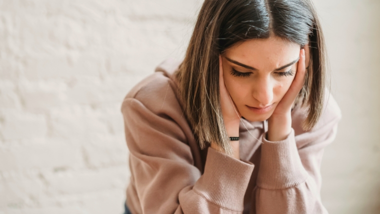 A sad looking woman with her head in her hands | How to Manage a Breakup When You Have Depression Practical Advice | Mindful Health Solutions