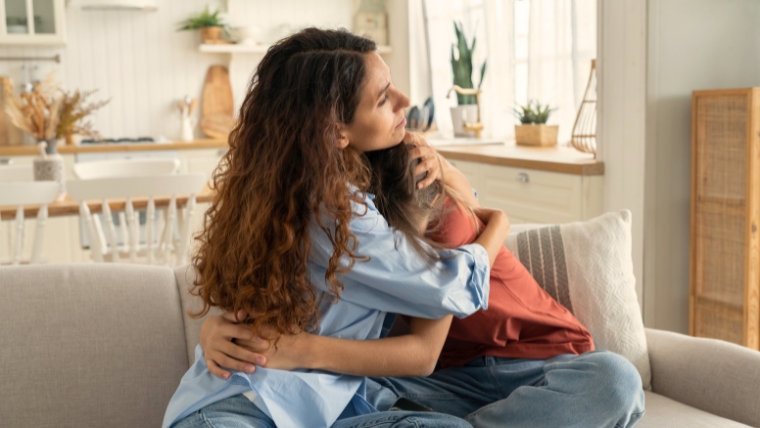 A mother comforting her daughter who is crying on the couch | Finding the Best Treatment for Your Child with Adolescent Depression | Mindful Health Solutions