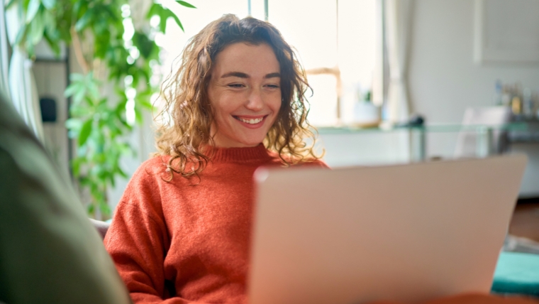 Relaxed happy young woman sitting on sofa using laptop | Managing Depression as a Freelancer: 10 Ways to Boost Mental Well-Being | Mindful Health Solutions