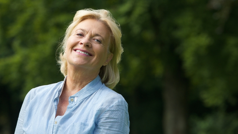 A woman smiling while standing outside | What Comes After TMS Treatment Embrace Pain-Free Living | Mindful Health Solutions