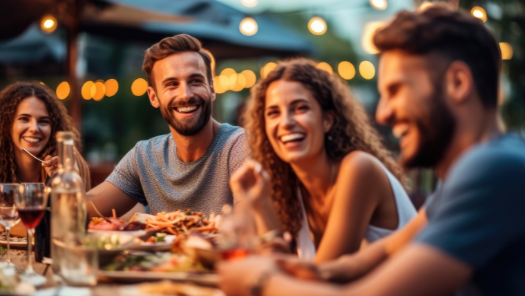 Group of friends laughing and enjoying dinner at outdoor restaurant during summer | Friendships and Mental Health 7 Tips for Building and Maintaining Healthy Relationships | Mindful Health Solutions